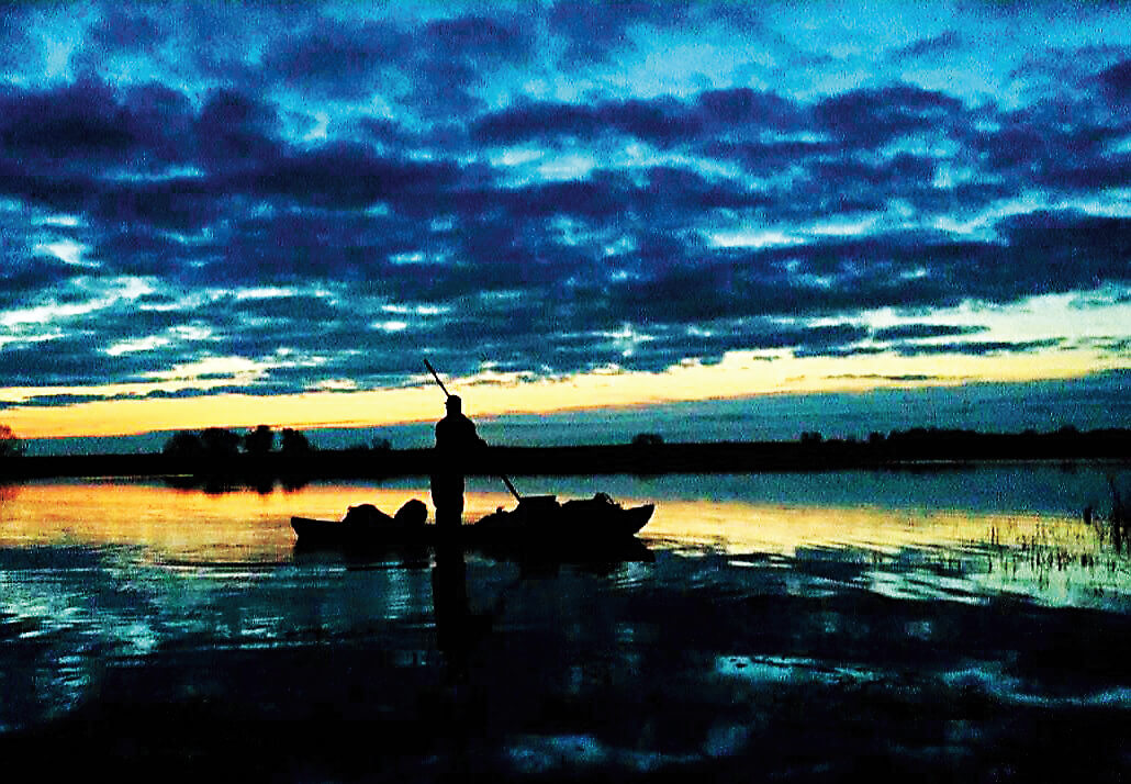 Duck hunter in marsh on a boat. Photo by Dan Kutchin
