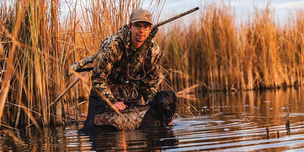 Hunter and retriever in wetland. Photo courtesy of North Dakota Tourism